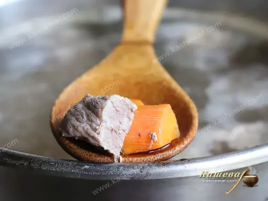 Beef and carrots on a wooden spoon