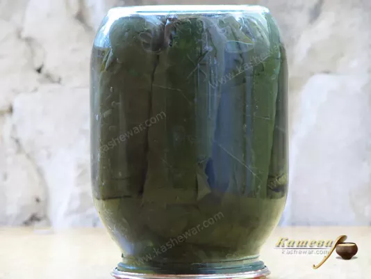 Rolling jars of cucumbers in grape leaves