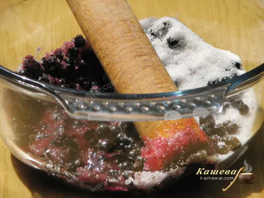 Rubbing black currant with sugar by hand