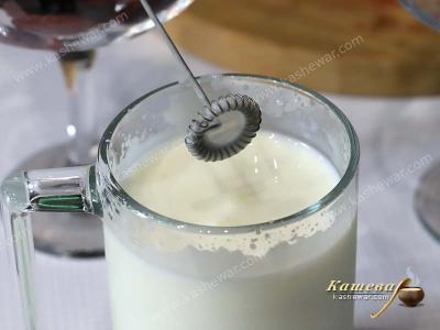 Kefir in a glass with a whisk.