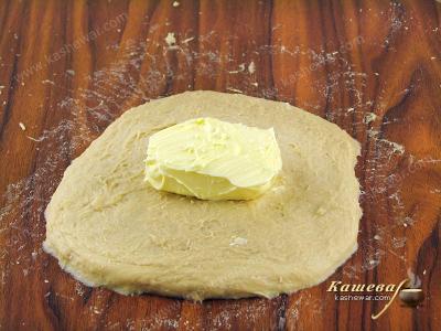 Расплющить тесто в виде прямоугольника и выложить в центр сливочное масло